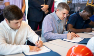 Alma Bryant High School seniors (left to right) Tyler Morgan, Logan Lyons and Thomas Durgin sign paperwork, officially accepting positions at Ingalls Shipbuilding. HII photo