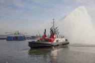 A tug spray from the Port of Durban’s new UMBILO tug while the Port of Richards Bay’s Usiba tug is lowered into the water in the background. (Photo: TNPA)