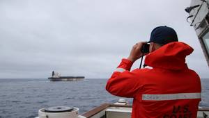A Coast Guard Cutter Munro (WMSL 755) crew member observes the oil tanker Bella 1 in the North Atlantic Ocean, Jan. 6, 2026. Munro’s crew monitored the vessel until it was seized by Coast Guard deployable specialized forces, with support from the Department of War, after Bella 1 violated U.S. sanctions and resisted initial boarding attempts off coastal Venezuela in late December. (U.S. Coast Guard photo)