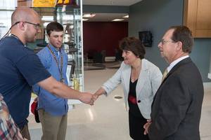 Apprentices Jason Marshall (left) and Matthew Stanley (center) greet Virginia Secretary of Education Anne Holton in the lobby of The Apprentice School before her tour led by the school’s director, Everett Jordan (right). Photo by Chris Oxley/HII