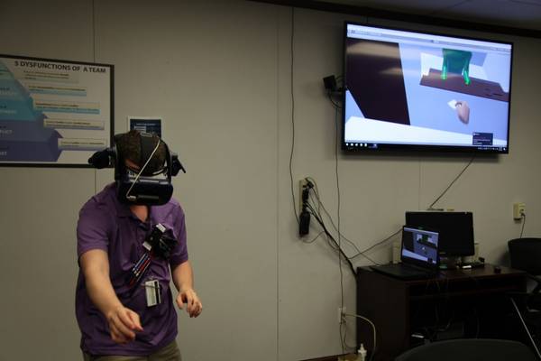 Computer Engineer Daniel Stith shows how to use the hands-free headset for the virtual reality simulation. (Photo: U.S. Navy)