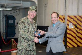 Don Hamadyk, Newport News Shipbuilding's director of research and development, presented the first 3-D printed metal part to Rear Adm. Lorin Selby, Naval Sea Systems Command’s chief engineer and deputy commander for ship design, integration, and naval engineering during a brief ceremony on USS Harry S. Truman (CVN 75). Photo by Matt Hildreth/HII.
