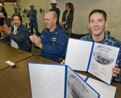 Doug Lounsberry (left) and Cmdr. Joe Tuite (center) applaud as Cmdr. Jon Haydel, commanding officer of San Diego (LPD 22), holds up the ceremonial document acknowledging the ship's custody transfer from Huntington Ingalls Industries to the U.S. Navy. Lounsberry is vice president of the LPD 17 Program at Ingalls. (Photo: HII)