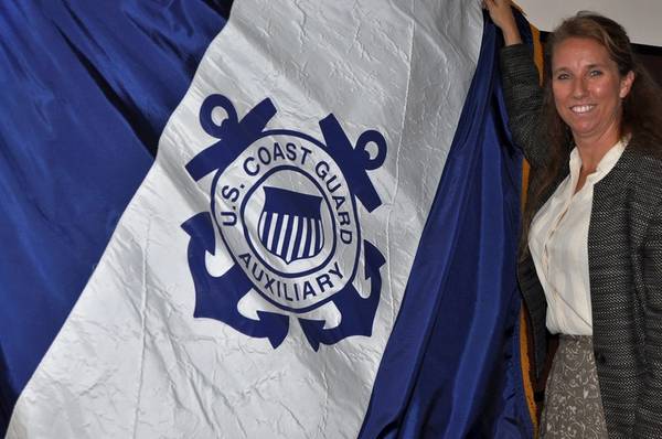 Michelle Thornton holds up the Coast Guard Auxiliary flag at Atlantic Area Command in Portsmouth, Va., July 6, 2015. Thornton, who works as a civilian employee for the Coast Guard, volunteers more than 20 hours every week to the Coast Guard Auxiliary where she serves as the district captain for Hampton Roads. (USCG photo by Melissa Leake)