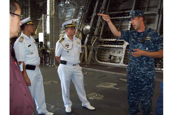 Cmdr. Dave Back (right), executive officer of USS Independence (LCS 2) Gold Crew, conducts a tour of his ship to attendees of the Sea Giraffe Users Group at Naval Base San Diego.  He is seen here showing the ship’s spacious mission bay to Cam Fung from Canada (left), and Capt. Charlie Songsawangthus and Cmdr. Sarawoot Chiyangcabut from Thailand. (Photo by Papola Kani, Consulate of Sweden, San Diego)