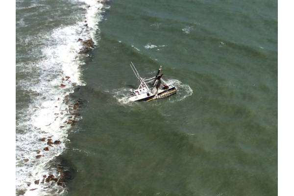 A shrimp boat is grounded on South Galveston Jetty after three fisherman aboard were rescued by the Coast Guard. (U.S. Coast Guard photo by Air Station Houston)