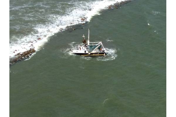 A shrimp boat is grounded on South Galveston Jetty after three fisherman aboard were rescued by the Coast Guard. (U.S. Coast Guard photo by Air Station Houston)